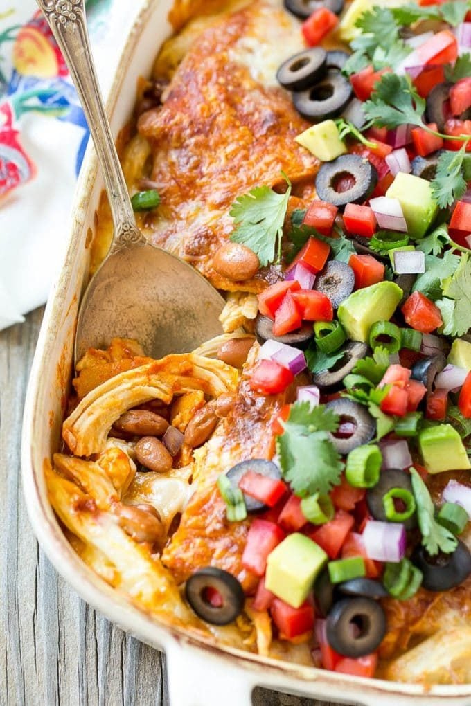 A chicken enchilada casserole with a serving spoon in it.