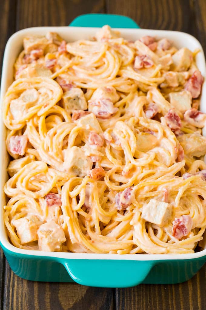 Cheesy spaghetti mixed with chicken and tomatoes in a baking dish.