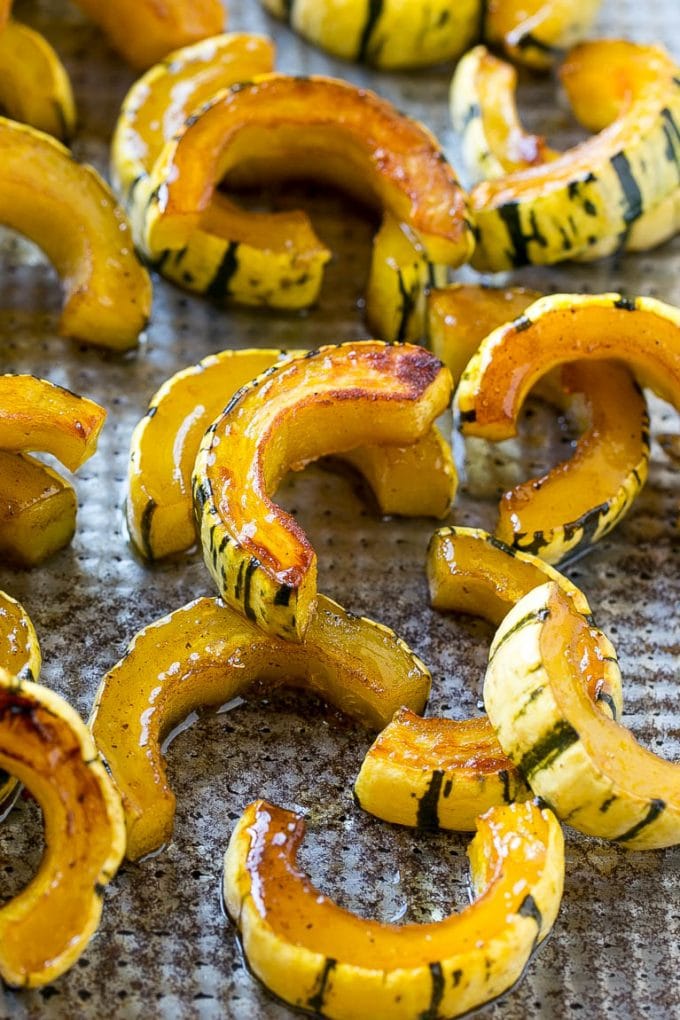 Roasted delicata squash on a sheet pan seasoned with brown sugar.