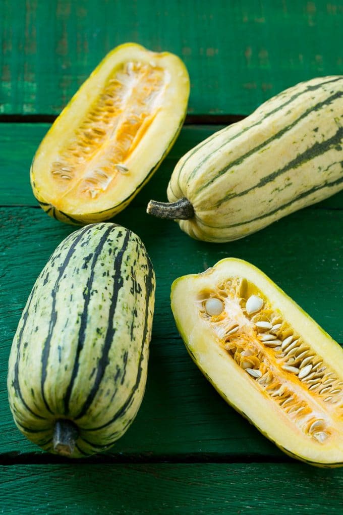 Raw delicata squash on a green board.