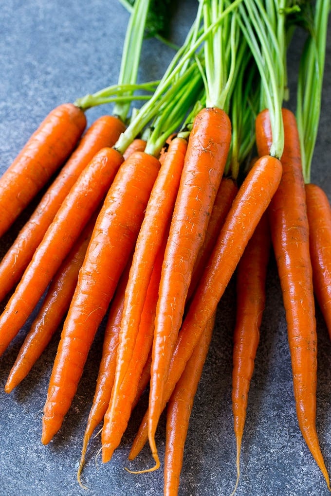 A bunch of baby carrots with green tops.