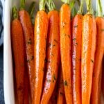 Honey roasted carrots in a baking dish, garnished with chopped parsley.