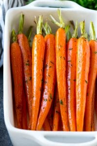 Honey roasted carrots in a baking dish, garnished with chopped parsley.