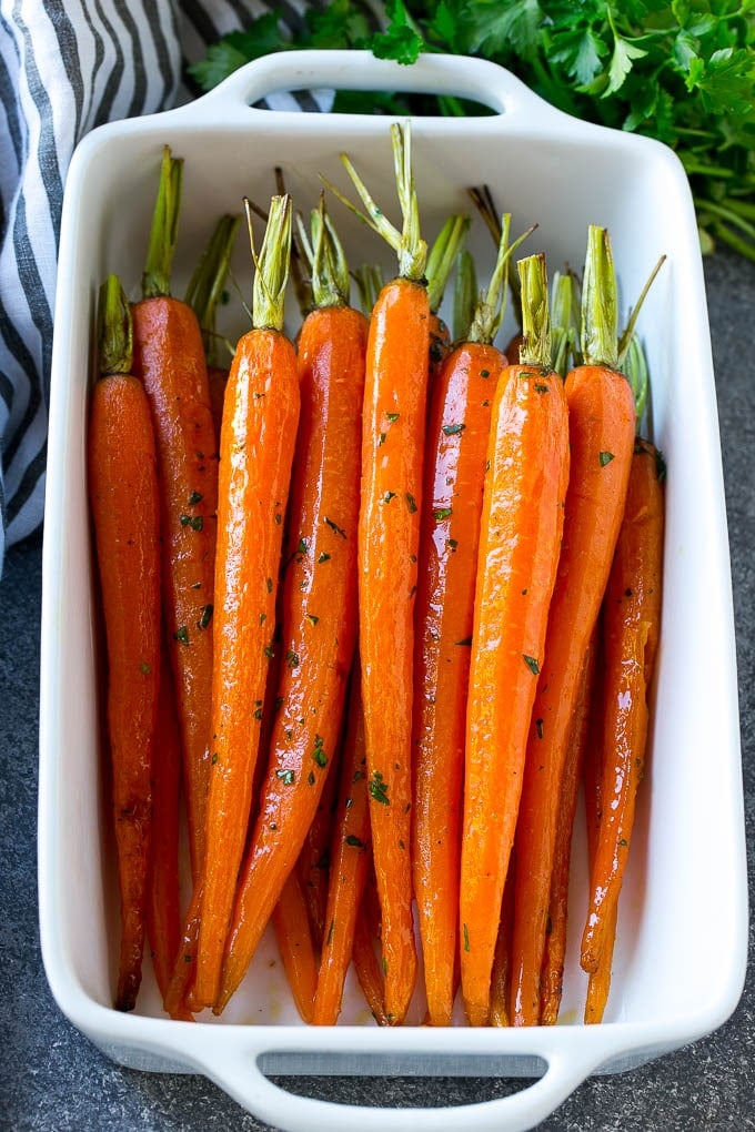 A baking dish of honey roasted carrots topped with parsley.