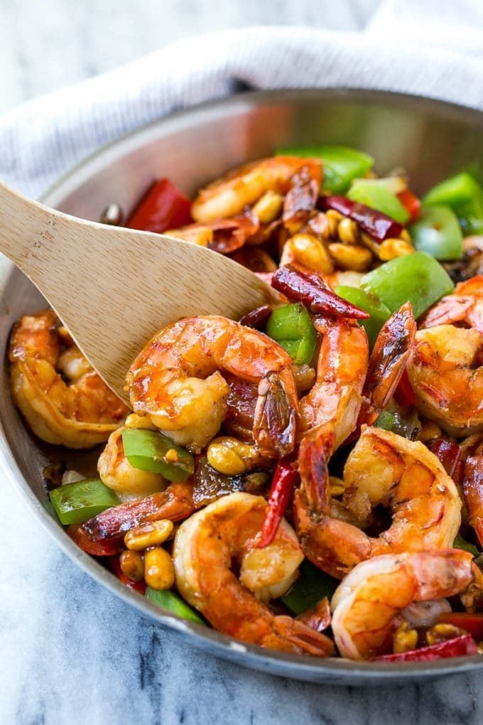 A serving spatula in a pan of Kung Pao shrimp.