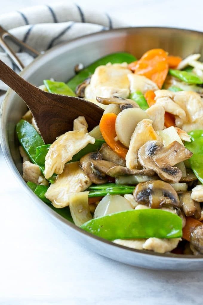 A skillet of moo goo gai pan with a serving spoon in it.