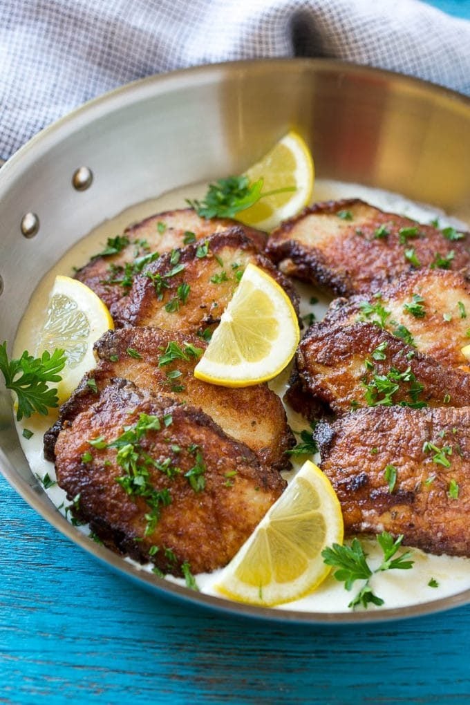 Slices of pork scallopini in a bed of creamy sauce with lemon and parsley.