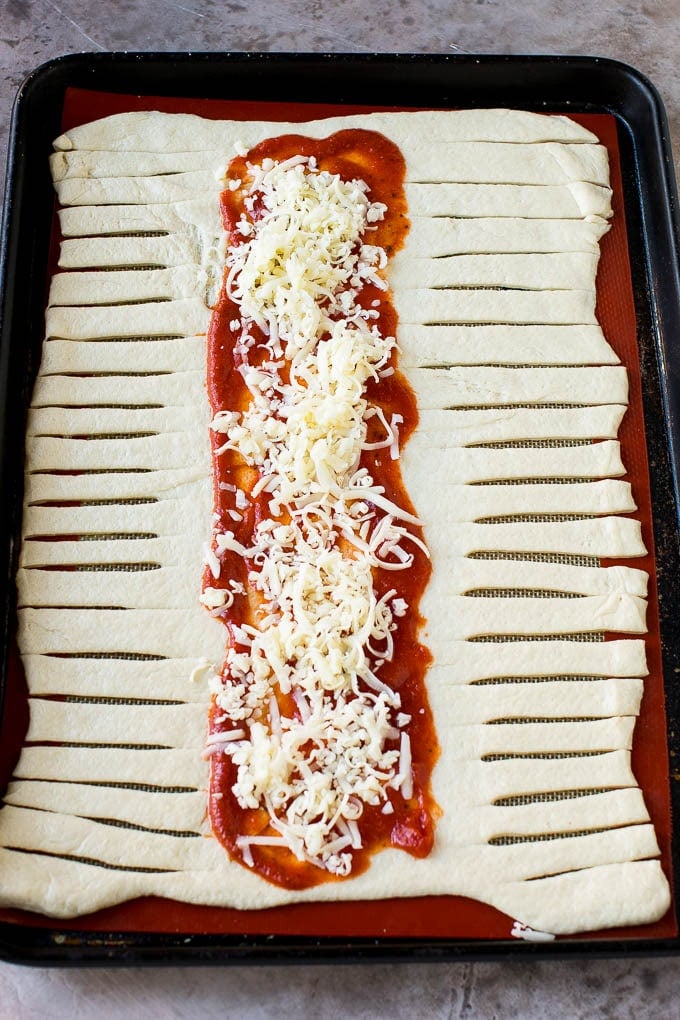 A sheet of pizza dough topped with tomato sauce and mozzarella cheese.