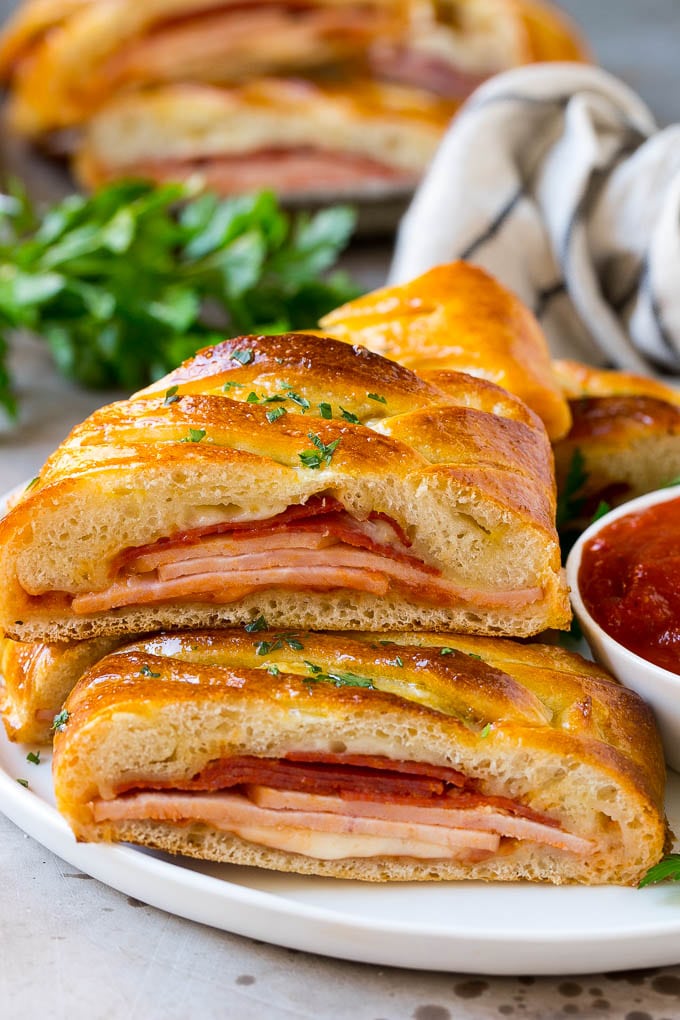 Italian stromboli layered with meats and cheese and served with a side of tomato sauce.