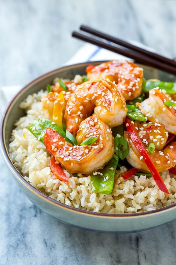 A bowl of shrimp stir fry and vegetables garnished with sesame seeds.