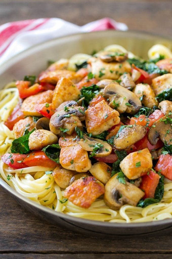 A pan of Tuscan chicken pasta with mushrooms in a creamy sauce.