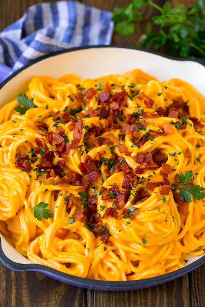 Butternut squash pasta in a skillet topped with bacon and parsley.