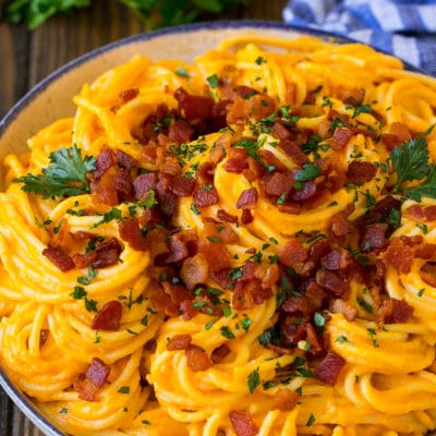 A bowl of creamy butternut squash pasta topped with bacon.