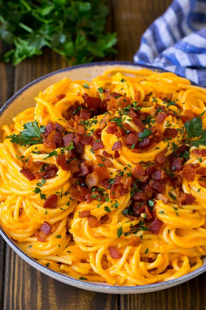 A bowl of creamy butternut squash pasta topped with bacon.