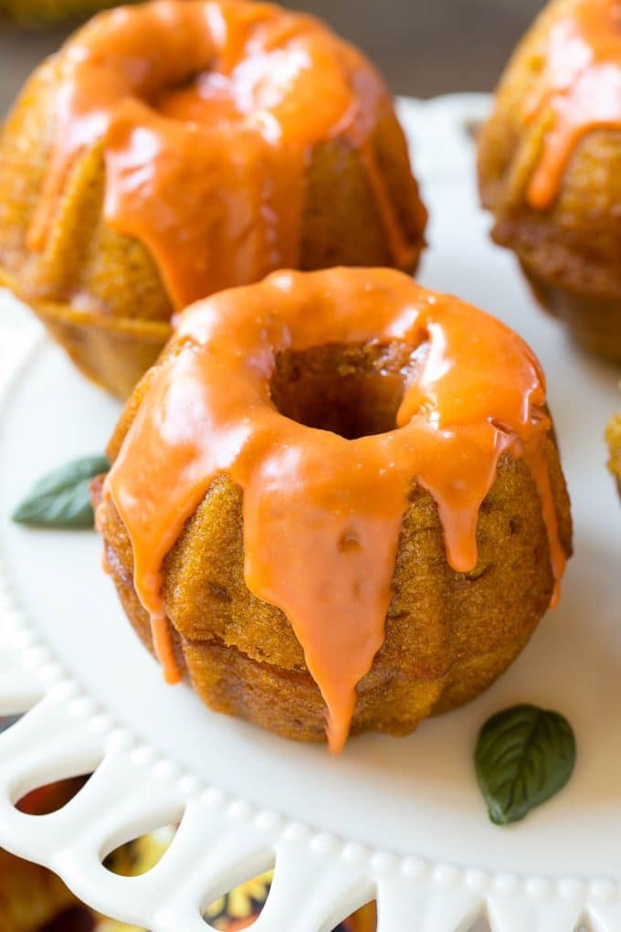 Two bundt cakes stacked together with orange colored ganache on top.