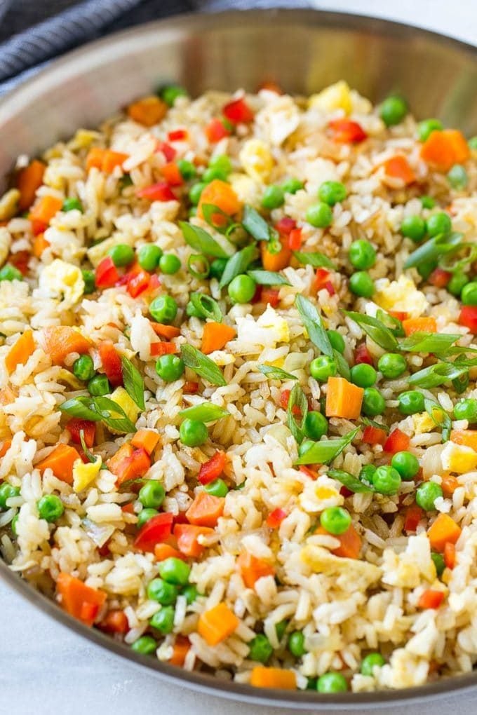 A skillet of veggie fried rice with eggs, peas, carrots and peppers.