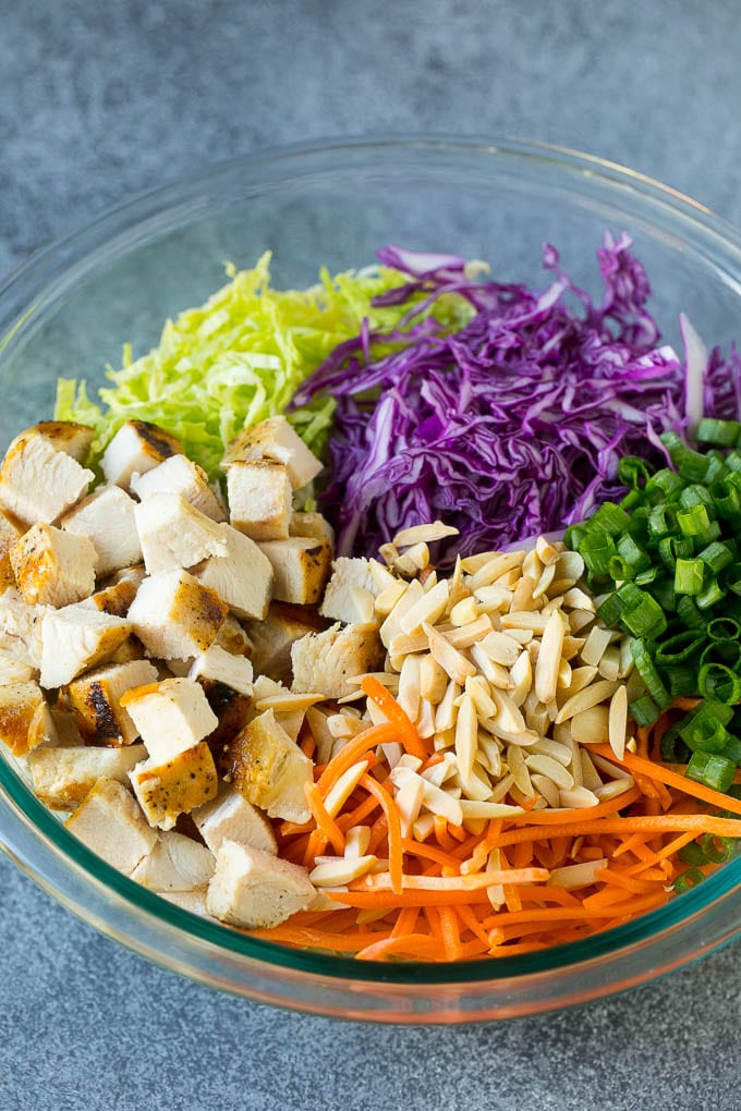 Cabbage, carrots, chicken, almonds and green onions in a bowl.