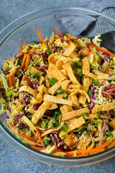 A bowl of Chinese chicken salad topped with wontons and sesame seeds.