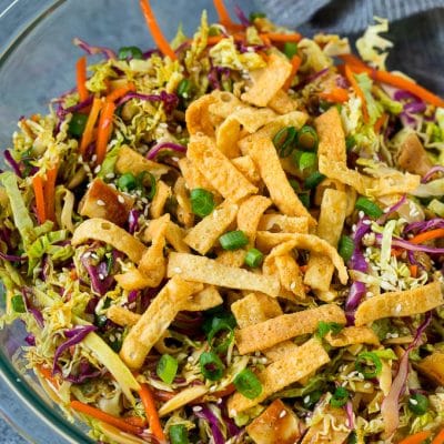 A bowl of Chinese chicken salad topped with wontons and sesame seeds.
