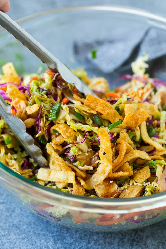 Tongs serving up a portion of Asian chicken salad.