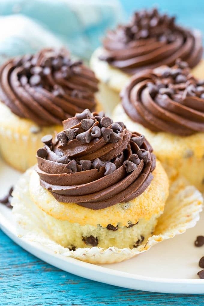 Chocolate chip cupcakes on a plate topped with chocolate frosting and mini chocolate chips.