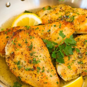 A pan of lemon pepper chicken garnished with parsley and lemons.