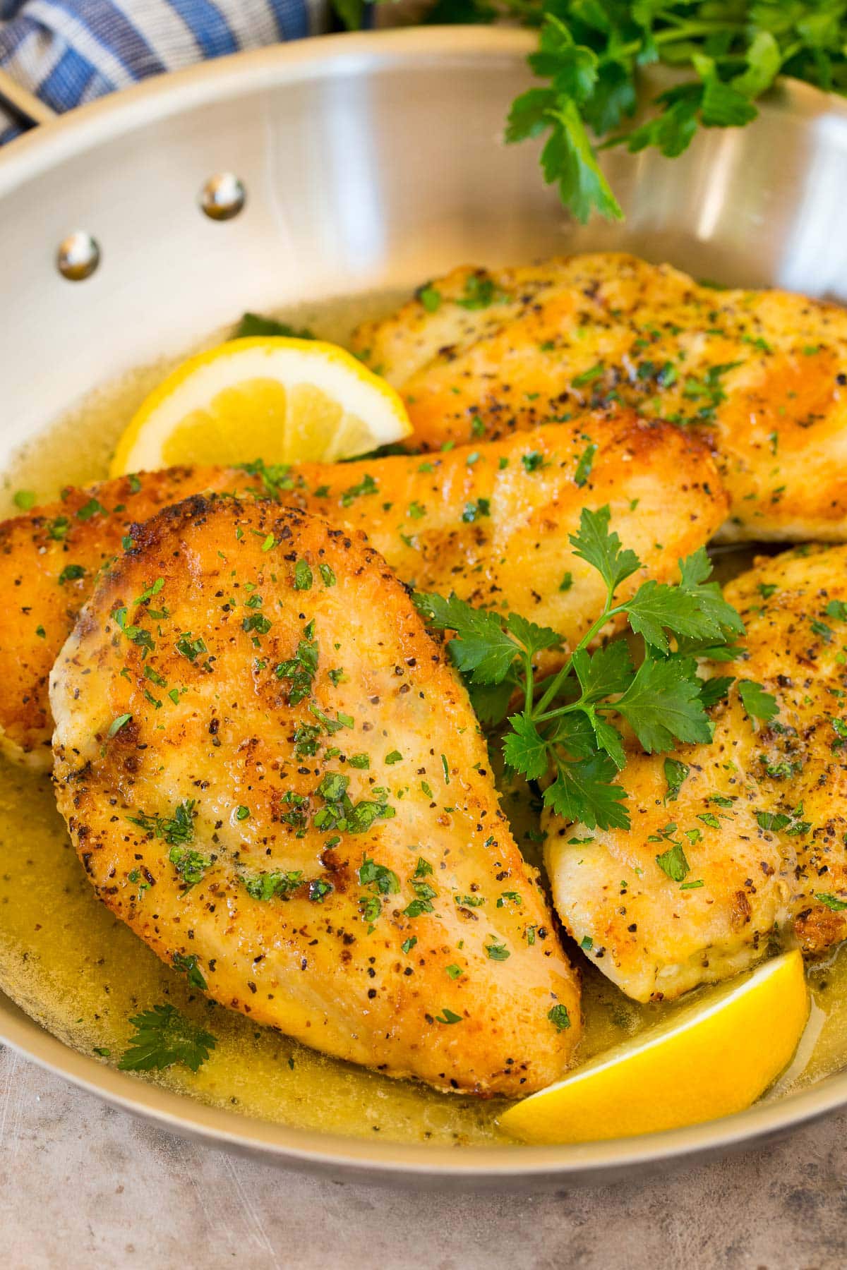 A pan of lemon pepper chicken garnished with parsley and lemons.