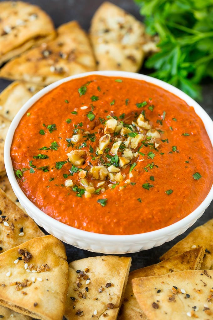 A bowl of muhammara topped with chopped walnuts and parsley.