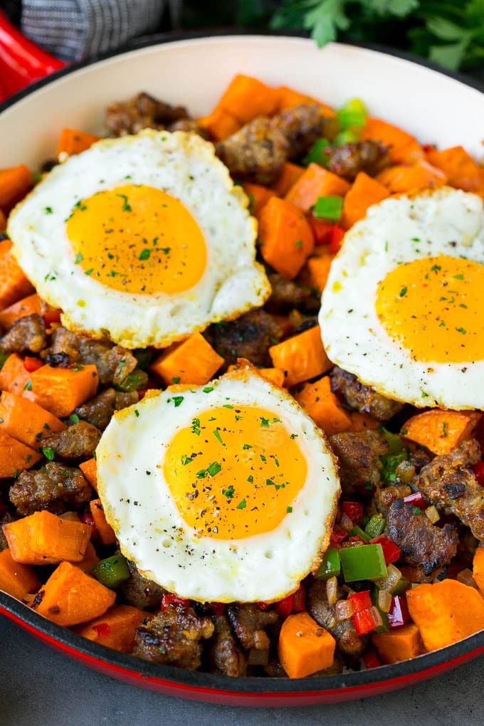 A pan of sweet potato hash topped with fried eggs.