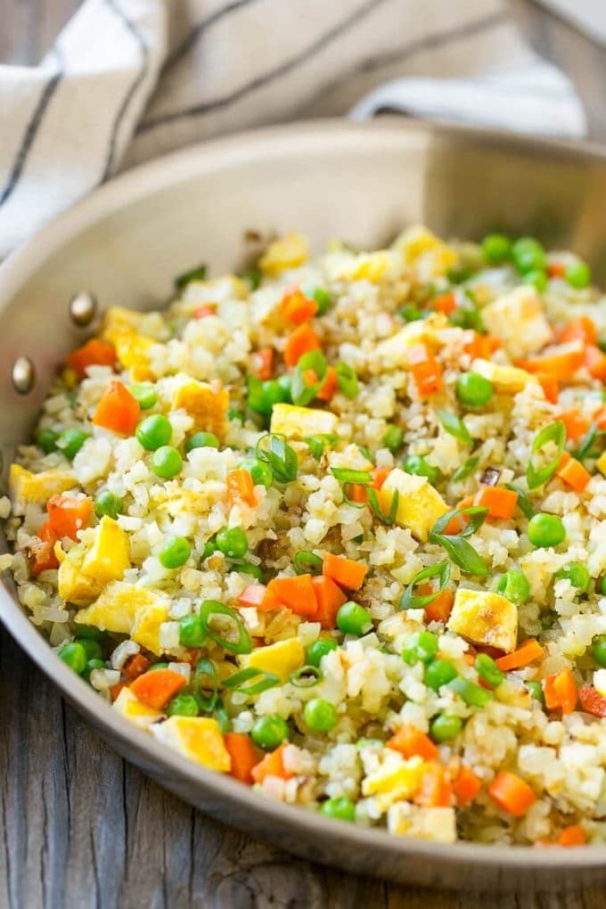 Cauliflower fried rice made with carrots, onions, peas, soy sauce and eggs, topped with green onions.