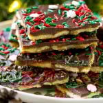 Christmas crack toffee topped with holiday sprinkles on a serving plate.