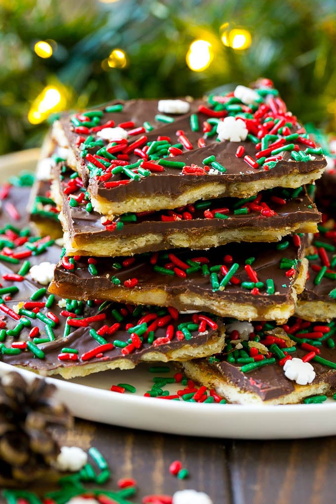 Christmas crack toffee topped with holiday sprinkles on a serving plate.