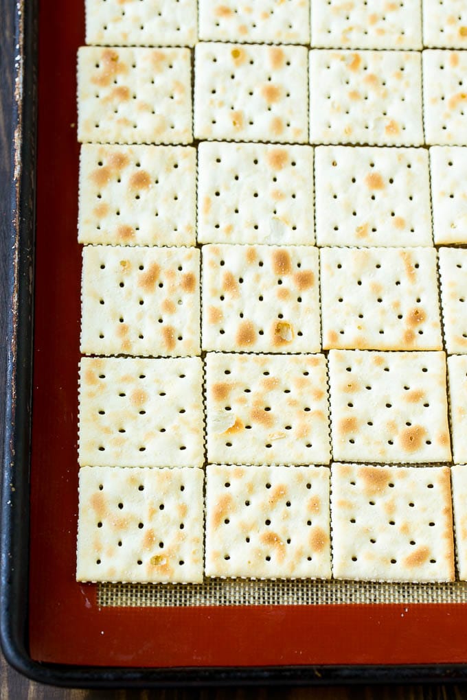 Saltine crackers lined up on a baking sheet.
