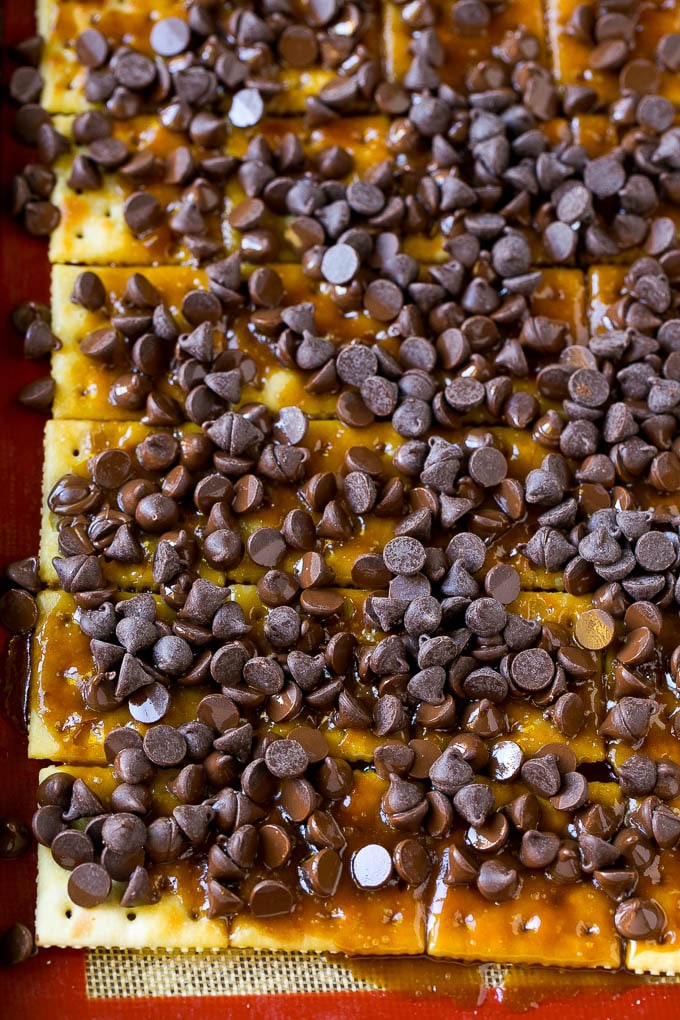 Chocolate chips on top of saltine crackers that have been coated in toffee.