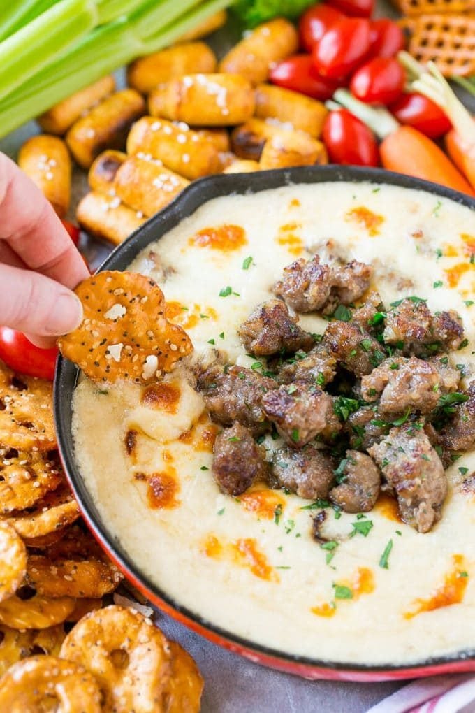 A pretzel chip scooping up some beer cheese dip.