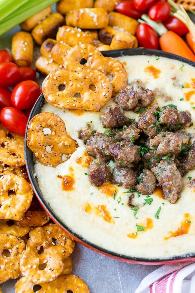 Beer cheese dip with pretzel chips scooping into it.