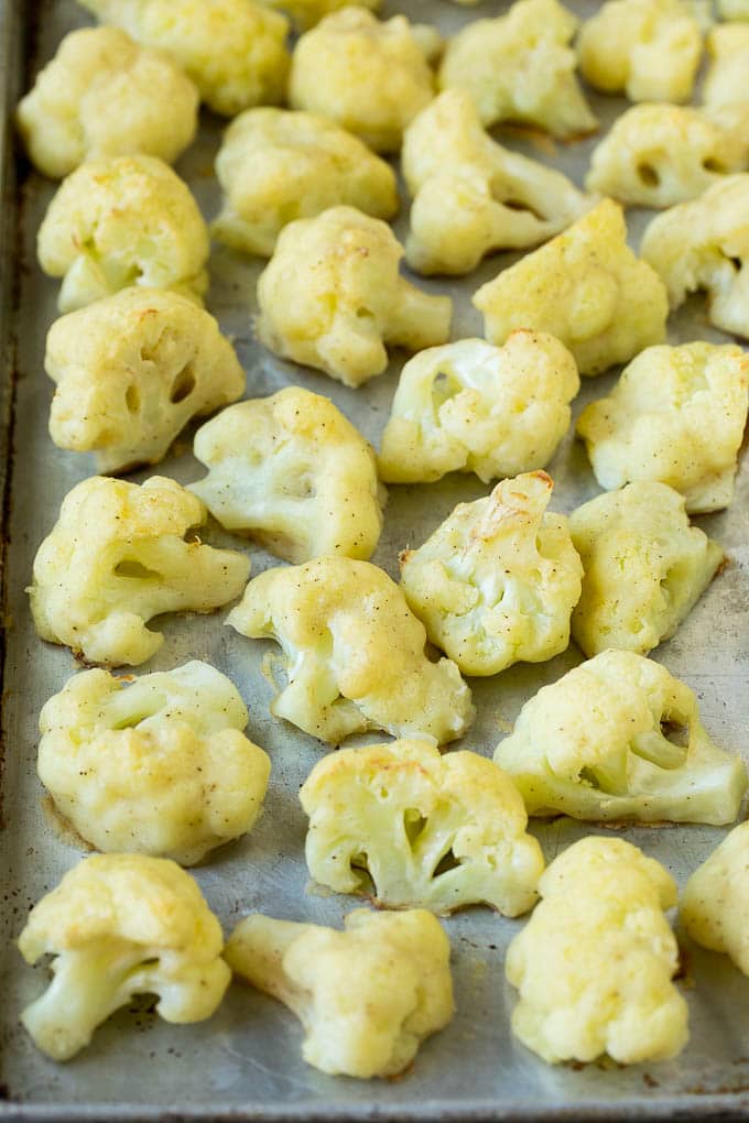 Battered and baked cauliflower florets on a sheet pan.