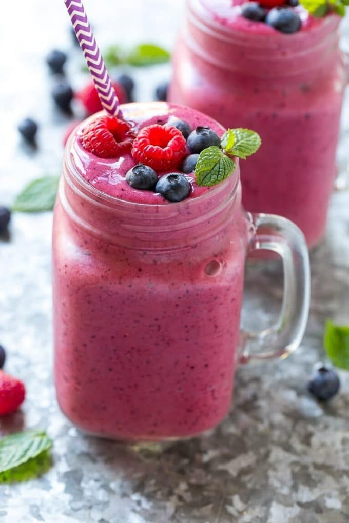 A mug filled with mixed berry smoothie and garnished with fresh berries.