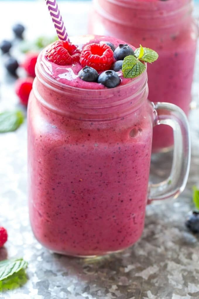 A glass of mixed berry smoothie with raspberries, blueberries and fresh mint for garnish.