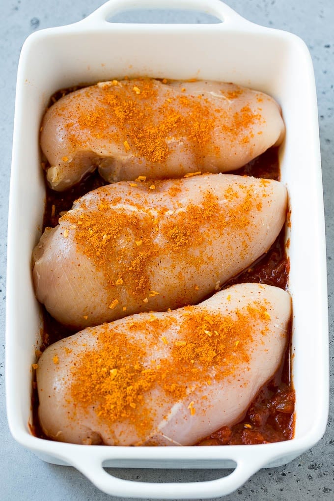 Chicken breasts in a baking dish topped with taco seasoning.