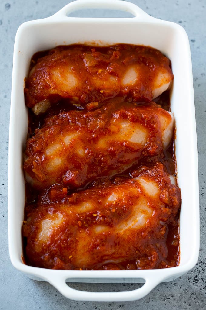 Chicken breasts in a baking dish coated with salsa.
