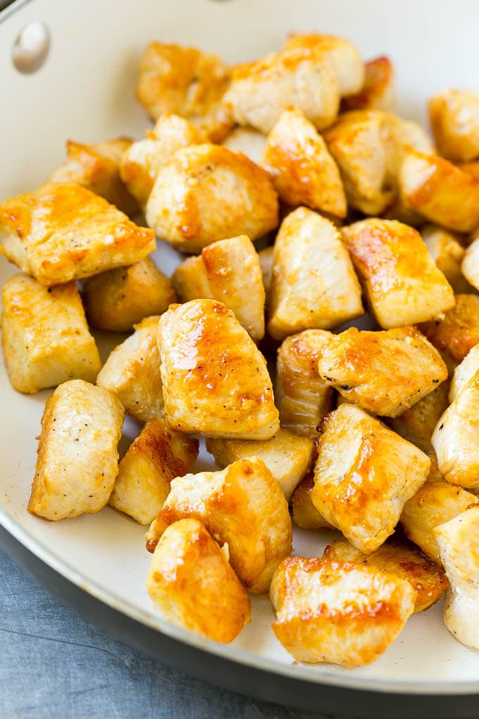 Seared chicken breast cubes in a pan.