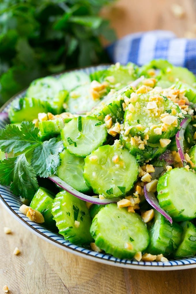 A serving bowl of Thai cucumber salad with red onion, peanuts and cilantro.