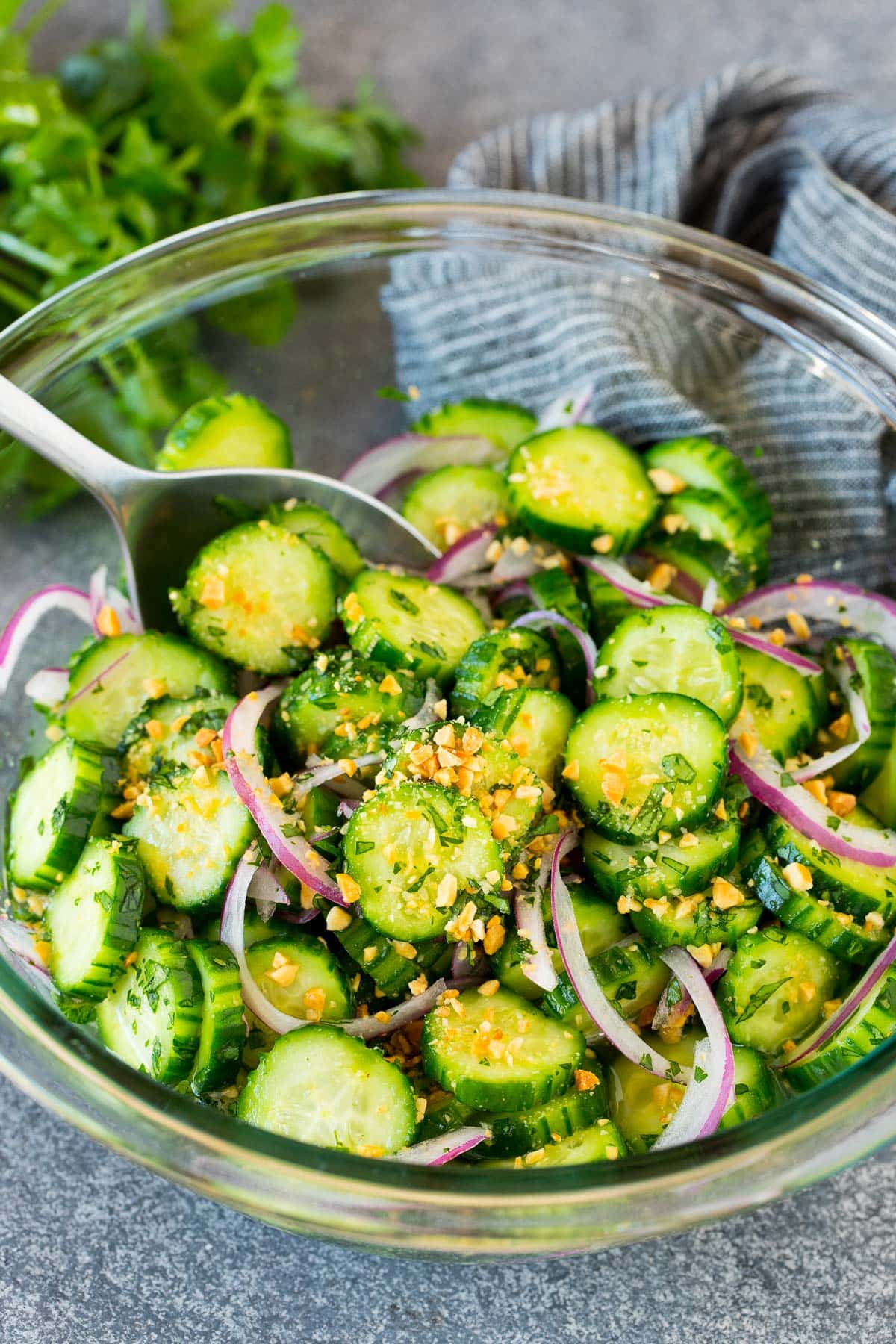 Thai cucumber salad in a bowl with a serving spoon.