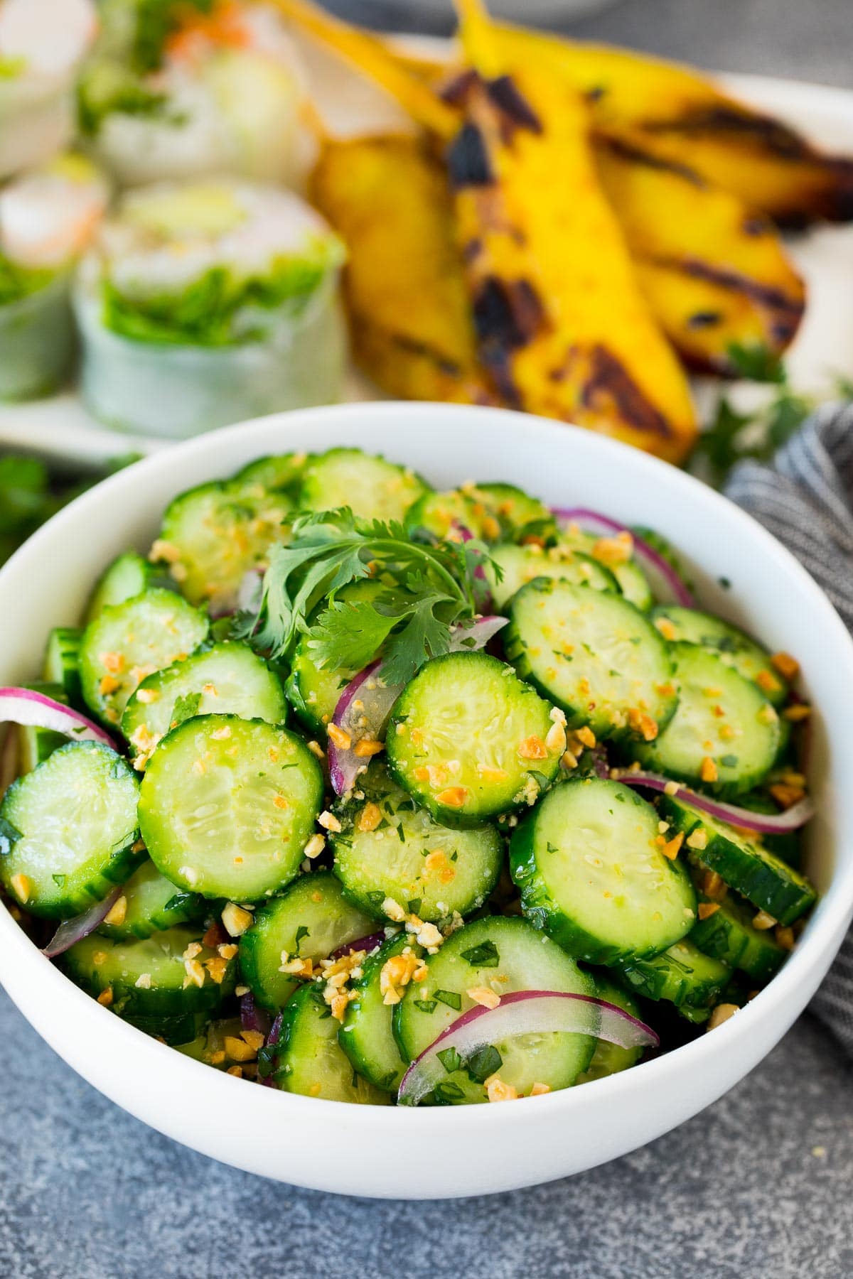 A bowl of Thai cucumber salad topped with peanuts and cilantro.