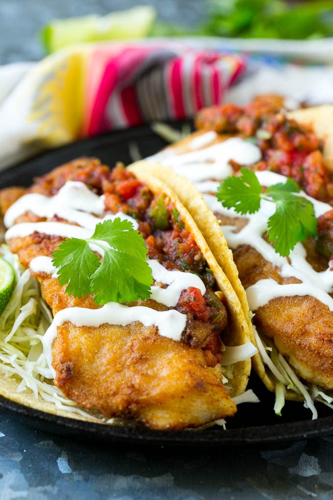 Baja fish tacos filled with fried fish, shredded cabbage, salsa and a creamy sauce.