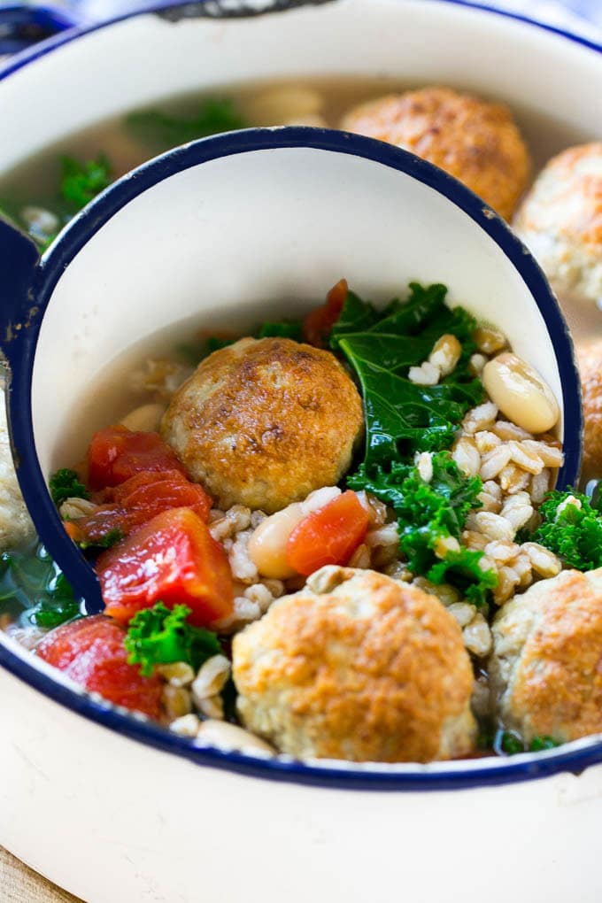 A ladle full of farro soup with meatballs.