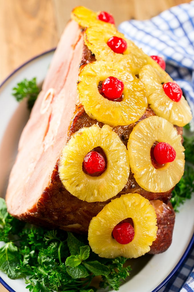 Ham with pineapple and cherries served on a bed of fresh herbs.