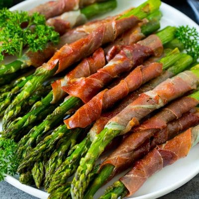 A plate of prosciutto wrapped asparagus garnished with fresh parsley.