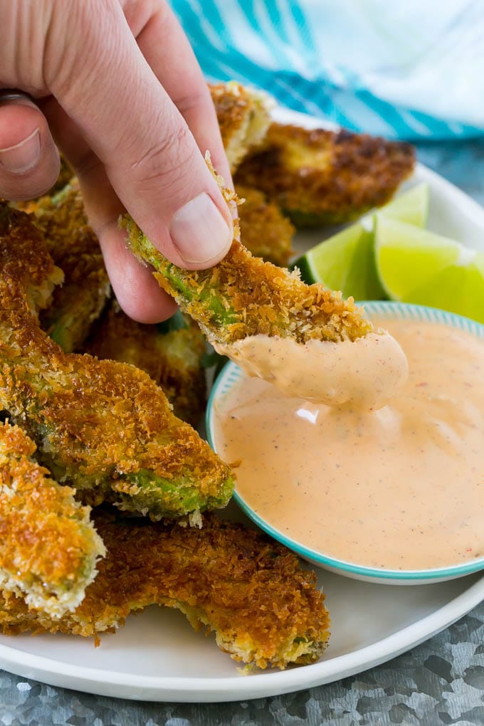 Avocado Fries Recipe | Fried Avocado | Avocado Fritters #avocado #appetizer #snack #dinneratthezoo A hand dipping an avocado fry into sauce.